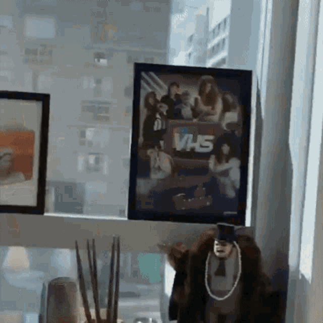 a framed picture of vhs sits on a window sill next to a stuffed animal