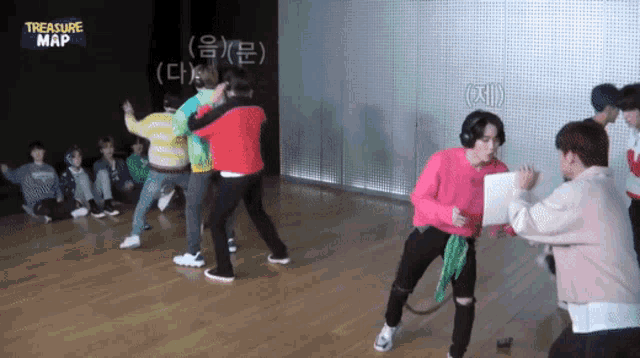 a group of young men are dancing in a room with treasure map written on the wall