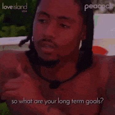a shirtless man is talking to another man while giving a thumbs up and asking what are your long term goals .