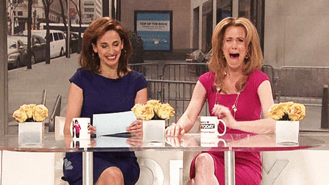 two women sitting at a table with a mug that says the today on it