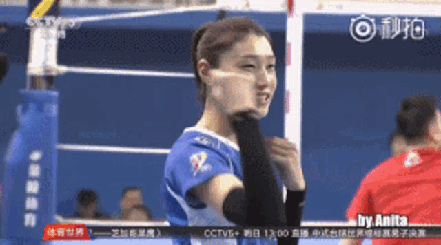 a woman in a volleyball uniform stands in front of a volleyball net with chinese writing on the screen