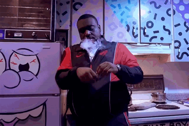 a man smoking a cigarette in front of a refrigerator that has a cartoon face on it