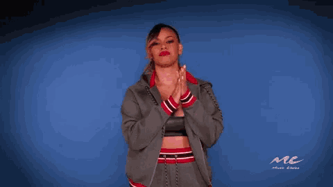 a woman applauds in front of a blue wall that says mc