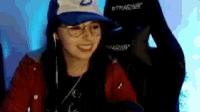 a woman wearing a blue hat and glasses is sitting in a gaming chair .
