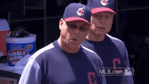 two baseball players are standing next to each other in a dugout with a bucket of bubble bubbles in the background