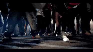 a group of people are walking down a street with their feet in the air
