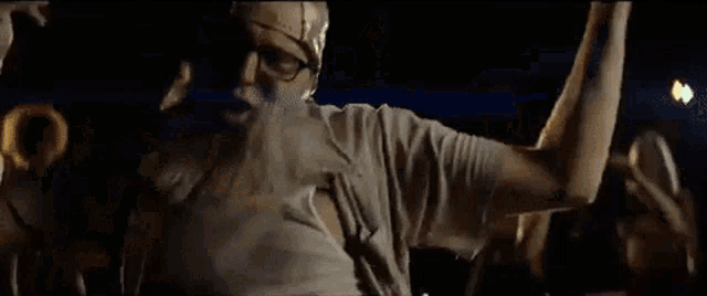 a man with glasses and a beard is dancing in front of a crowd of people .