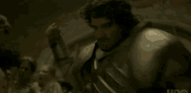 a man in armor is standing in front of a group of people in a dark room .