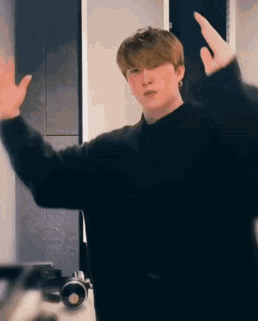a young man in a black sweater is making a funny face .