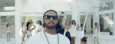 a man in sunglasses stands in front of a group of women