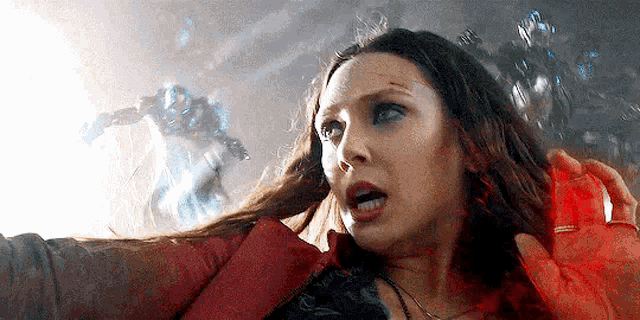 scarlet witch is holding a red object in her hand while fighting a robot in a movie .
