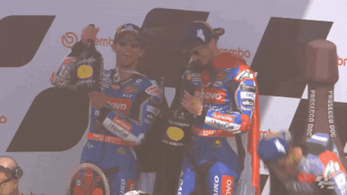 two motorcycle racers are standing on a podium with lenovo written on their uniforms
