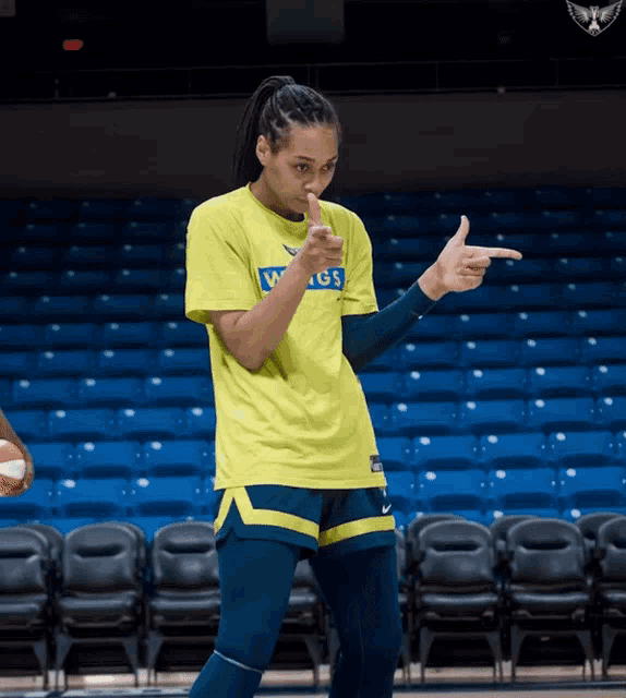 a female basketball player wearing a yellow shirt that says wings on it