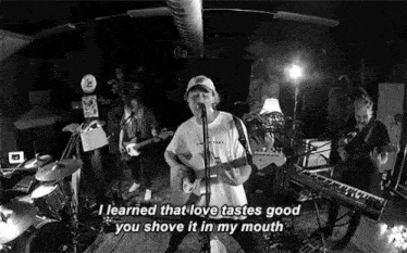a man is singing into a microphone while playing a guitar in front of a band .