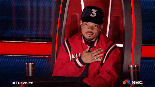 a man wearing a hat with the number 3 on it sits in a chair