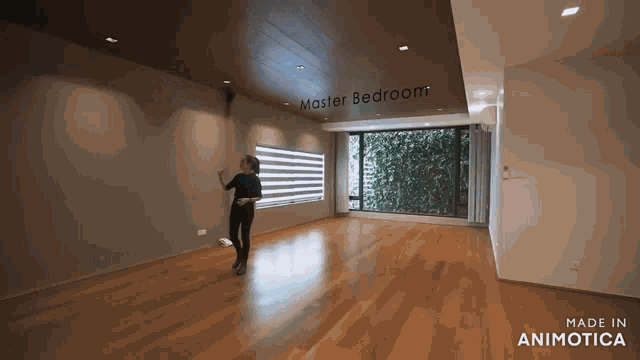 a woman is dancing in a room with a sign that says " master bedroom "