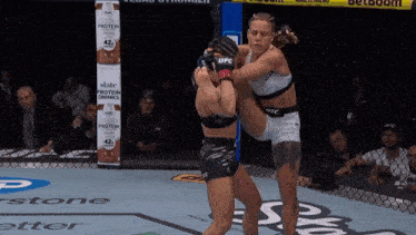 two women are fighting in a boxing ring with a sign that says protein drinks on it