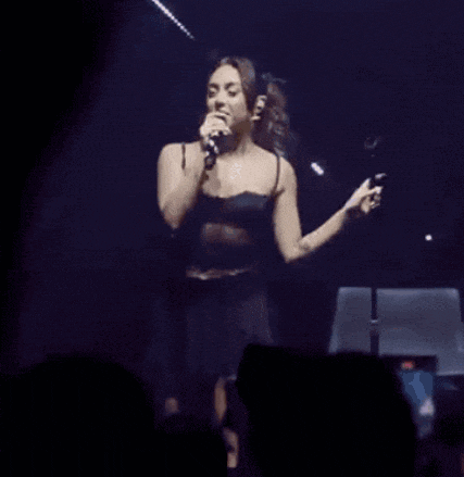 a woman is singing into a microphone in front of a crowd