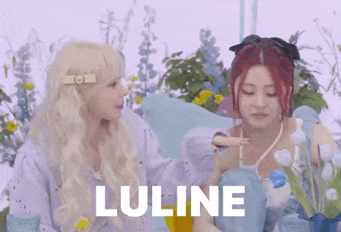 two girls are sitting next to each other in front of flowers and the word luline is on the bottom .