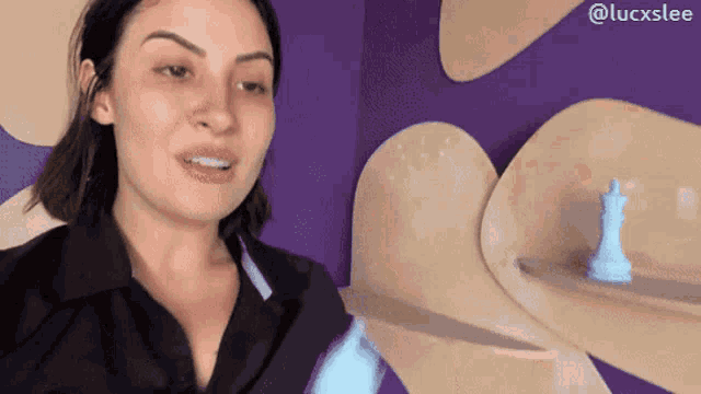 a woman is standing in front of a purple wall with a chess piece in the background