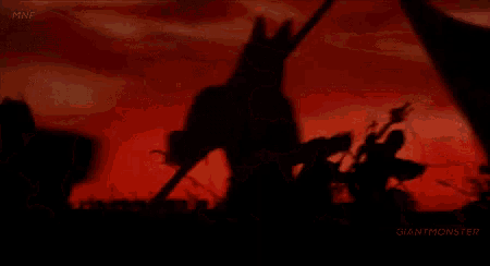 a group of people are standing in front of a red sky in a silhouette .