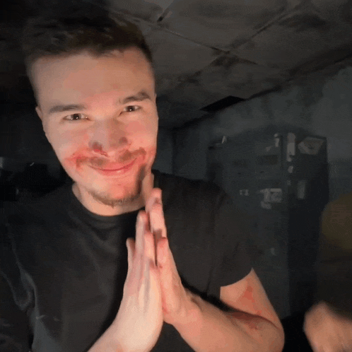 a man with blood on his face is smiling with his hands together