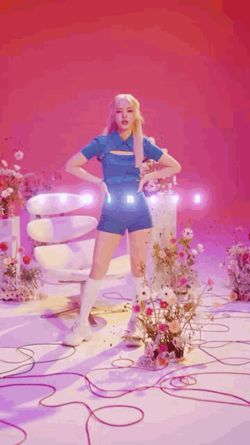 a woman in a blue outfit is standing in front of a chair and flowers .