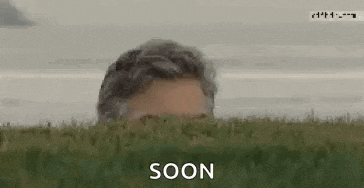 a man is peeking out from behind a lush green field with the words `` soon '' written on the bottom .