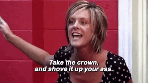a woman is standing in front of a red wall and saying `` take the crown and shove it up your ass '' .