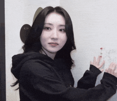 a woman wearing a black hoodie is standing in front of a sign that says 430