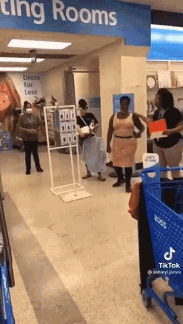 a woman in a pink dress is standing in front of a sign that says " dressing rooms "