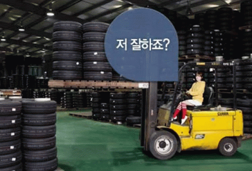 a woman is sitting on a forklift in a warehouse filled with tires .