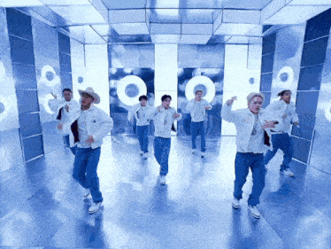 a group of men are dancing in a room with speakers on the wall