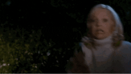 a woman in a blue shirt is screaming in a dark room