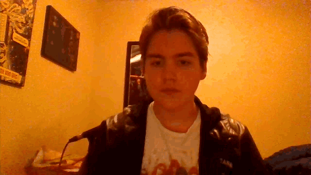 a young man wearing a black jacket and a white shirt with a t-shirt that says tam