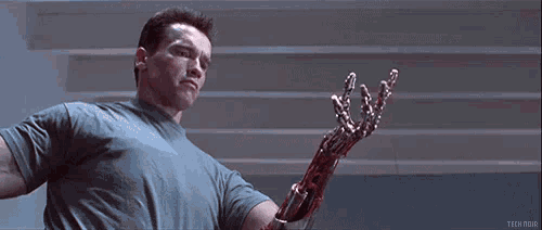 arnold schwarzenegger is holding a bloody robotic arm in terminator 2 judgment day .