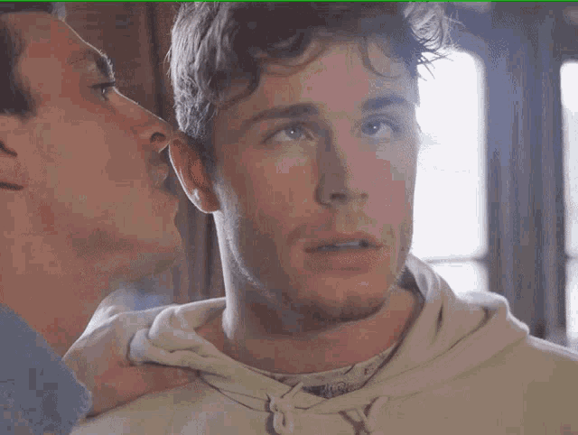 two men are looking at each other and one has a hoodie on