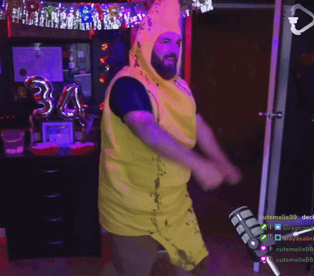 a man in a banana costume is dancing in front of a microphone with the number 34 balloon in the background