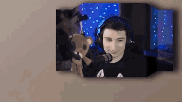 a young man wearing headphones is holding a stuffed animal .