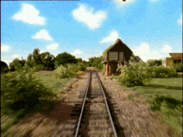 a train is going down the tracks in front of a building