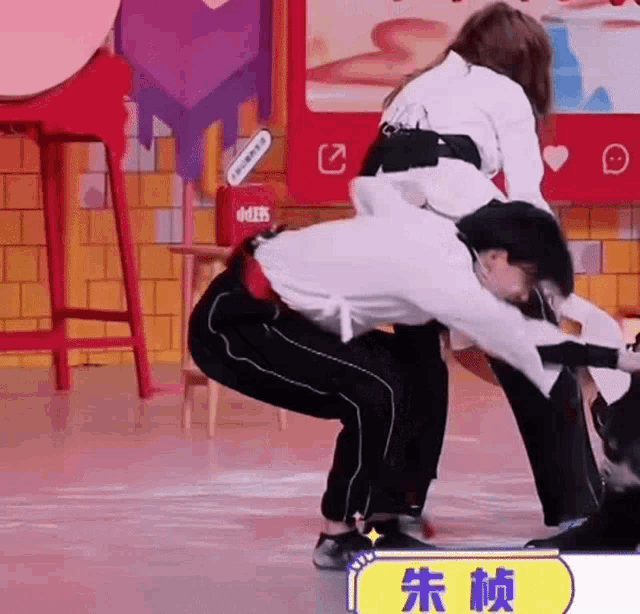 a man is carrying a woman on his back in a room with chinese writing on it .