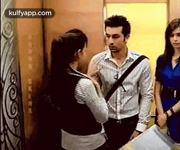 a man and a woman are standing next to each other in an elevator talking to each other .