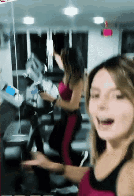 a woman in a pink tank top is riding an exercise bike in a gym
