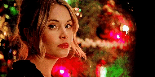 a woman is standing in front of a christmas tree with christmas lights .