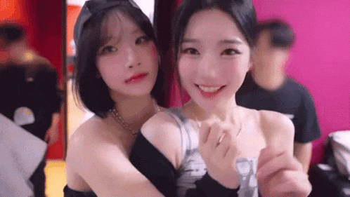 two young women are hugging each other in a room and smiling for the camera .