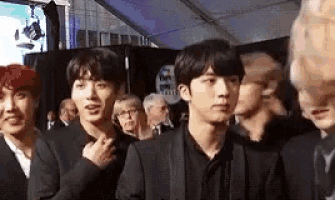 a group of young men in suits are standing next to each other .