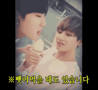 two young men are eating an ice cream cone with foreign writing on the bottom
