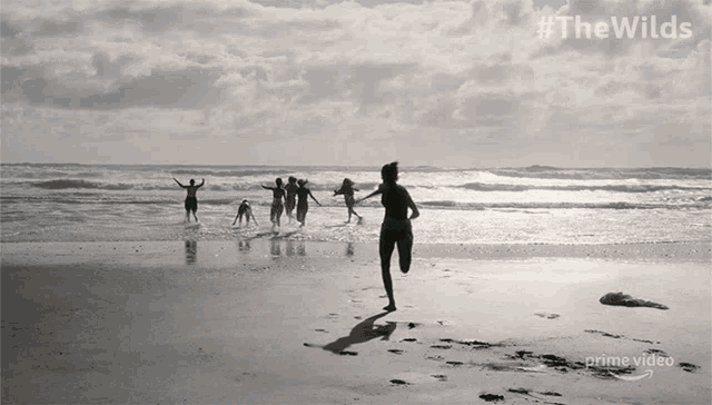 a group of people running on a beach with #thewilds