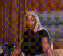 a woman with a crown on her head is sitting in a room .