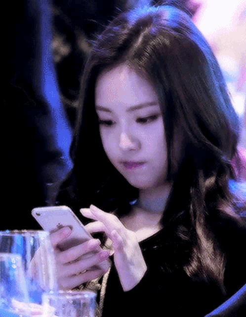 a woman is looking at her phone while sitting at a table with a glass